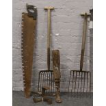 A selection of hobbing feet, two man wood saw, hay fork and one similar.