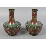 A pair of early 20th century Chinese cloisonne vases, decorated on red grounds with prunus blossom