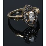 A 9ct gold and diamond ring. With a marquis cut principle stone under a navette border of cognac