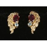 A pair of 9ct gold ruby and blue topaz foliate scroll ear studs.