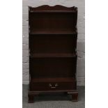 A mahogany waterfall bookcase with single drawer and raised on ogee bracket feet.