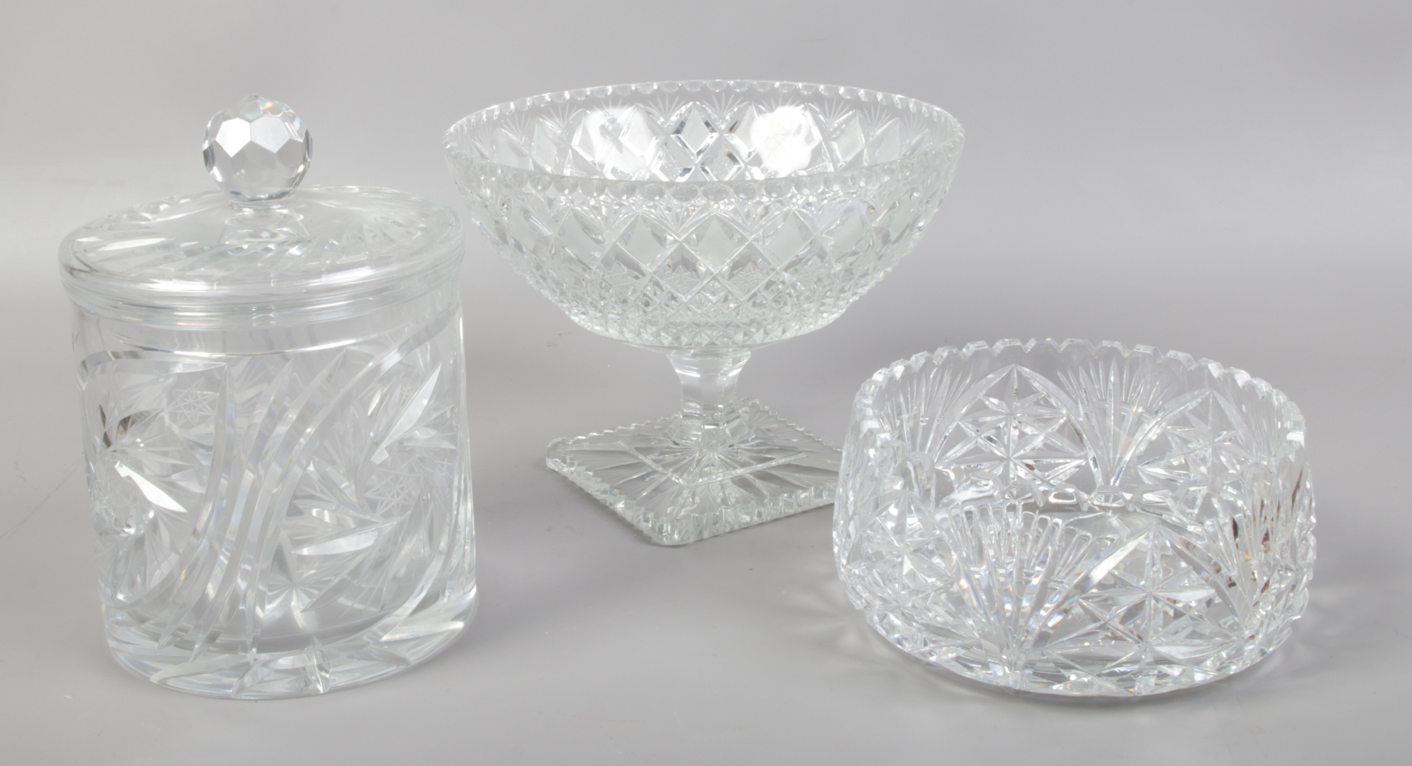 A cut lead crystal pedestal bowl, another bowl and a biscuit jar and cover.