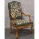 A carved walnut French style open armchair with embroidered upholstery.
