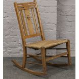 An Arts & Crafts oak rocking chair with rush seat.