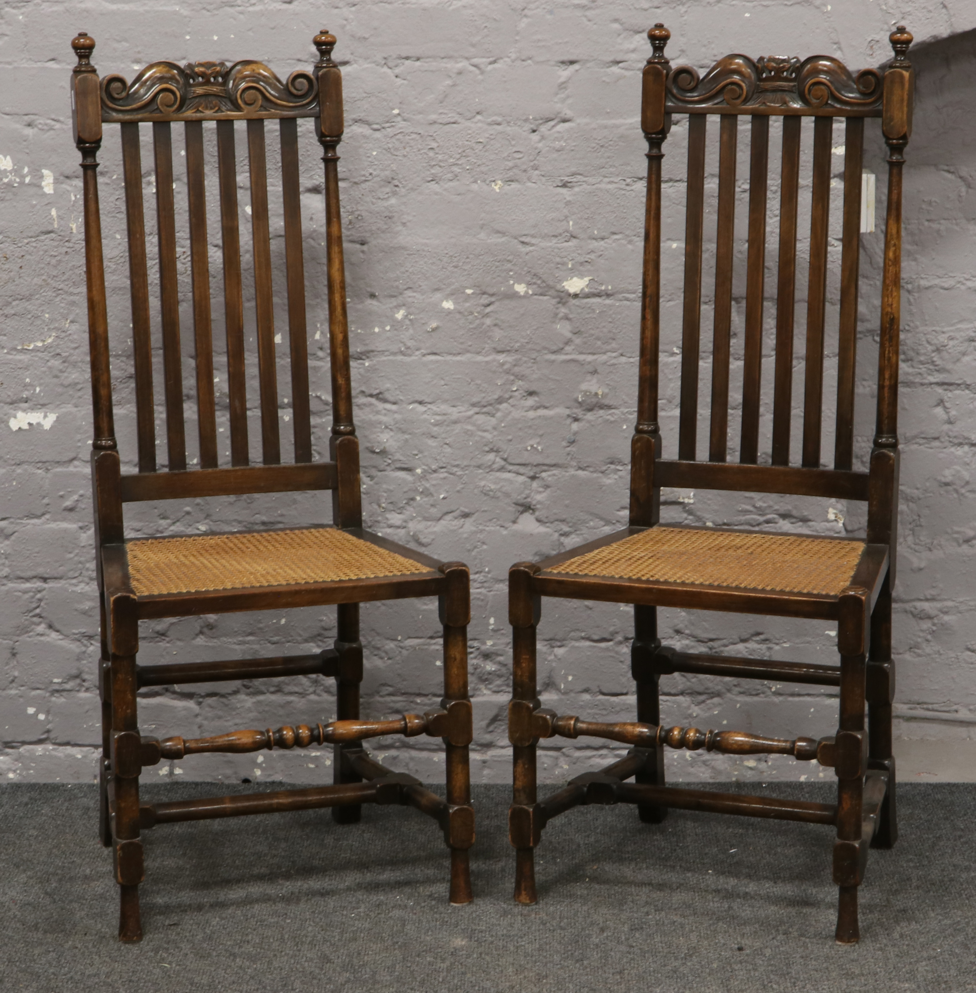 A pair of Jacobean style stick back side chairs with carved scroll formed cresting rails and