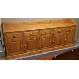 A large pine five cupboard sideboard with shaped splashback, 243cm wide, 54cm drop, 17cm high.