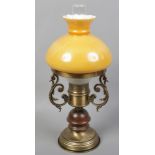 A brass effect table lamp in the form of an oil lamp with amber and opaque glass shade.