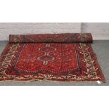 A wool hand woven eastern Kayam red ground rug with central design, 120cm x 150cm.