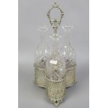 A silver plated trefoil decanter stand with pierced decoration and three glass decanters.
