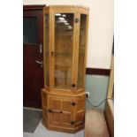 Mouseman oak corner cupboard, with angled sides, glazed upper part and panelled base (key in