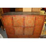 An 18th Century Eastern Tibetan painted and panelled wood cabinet, decorated in a red base and