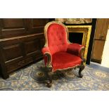 Victorian carved rosewood nursing chair of Gothic design, upholstered in red buttoned cloth