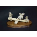 A 19th century Japanese ivory figure group, featuring three young boys playing on a see-saw of