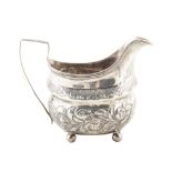 Georgian silver milk jug, compressed oval body with embossed floral decoration on 4 ball feet,