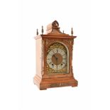 An early 20th century German bracket clock. The walnut case has a caddy top pediment with brass