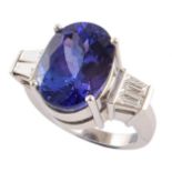 Tanzanite single stone platinum ring with baguette diamond set shoulders , the oval mixed cut