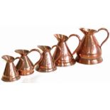 Five graduated copper jugs