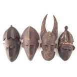 Four African masks carved in the Bambara and Burkina Faso styles.