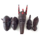 Five African masks carved in the Dogon and Senufo tribal styles