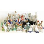 Twenty four Staffordshire figures including a Greyhound inkwell and two cow creamers. Condition