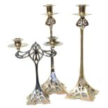 Two Art Noveau style white metal candle sticks together with a small matching candelabra.