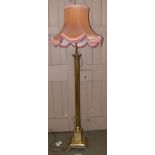 Brass Corinthian column standard lamp complete with pink shade. Condition reports are not