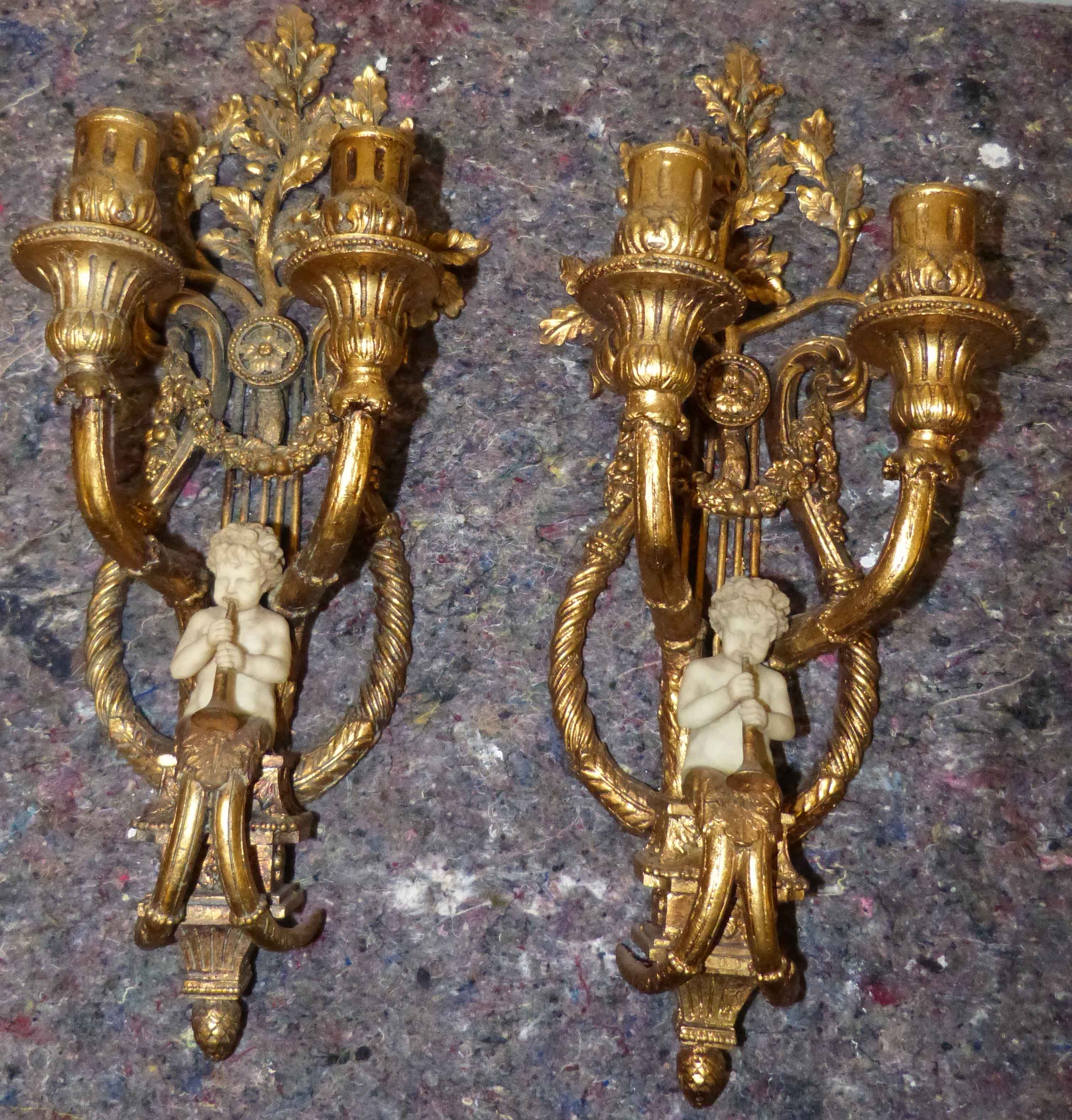 A pair of reproduction gilt metal effect double wall sconces decorated with Parian effect cherub