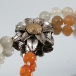 A two row agate bead necklace, to a two colour flower head clasp, stamped '14k'