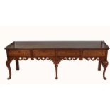 A large antique style fruitwood dresser base, fitted with four short drawers, having a shaped apron,