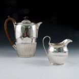A silver coffee pot and milk jug, the coffee pot engraved with a crest, both with gadrooned lower