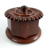 A 19th century mahogany tobacco box, of circular form, the lid with gadrooned edge, faceted body