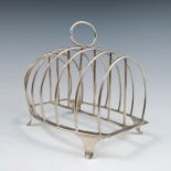 A Georgian silver seven bar toast rack, with loop handle and raised on four scroll feet, London