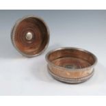 A pair of silver plated bottle coasters, with gadrooned edge, the turned wooden base with button