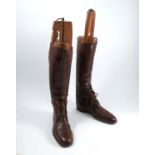 A pair of brown leather gents riding boots, with lace up fronts, together with wooden trees,