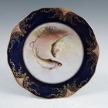 A Royal Worcester plate, decorated with fish by W H Austin, to a blue and gilt border, dated circa