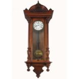 A mahogany cased Vienna style wall clock, the case having carved decoration, with white enamel dial,