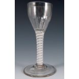 An 18th century English drinking glass, with faceted bowl, the stem with double opaque twist, raised