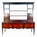 An antique oak dresser, having plate rack over three short drawers, over shaped apron, raised on