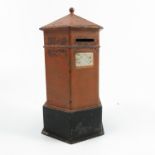 A painted metal post box, of hexagonal form, painted with red and black, with white plaque Next