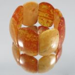 An amber bracelet, the eight rectangular panels strung on elastic, together with a three panel amber