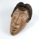 A carved and painted tribal mask, of a female with black hair, height 13ins