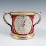 A 19th century English porcelain two handled loving mug, with two reserves decorated in gold