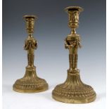 A pair of gilt metal candlesticks, decorated in the Classical style with swags, leaves and