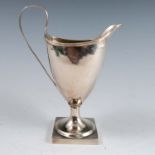 A Georgian silver cream jug, of helmet form, with ribbed edge and handle, raised on a square