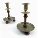 A pair of Islamic engraved brass candlesticks, with polished hardstone supports inlaid with precious