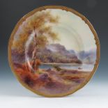 A Royal Worcester plate, fully decorated with a figure in a boat in a highland landscape with trees,