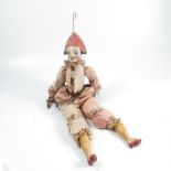 A harlequin doll, with painted composition face and lower limbs with silk covered fabric body,