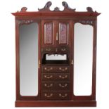 An Edwardian mahogany wardrobe, with a carved broken swept pediment above two carved doors, above