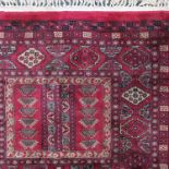 An Eastern silk style rug, with repeating symbols to a red ground, 56ins x 39ins