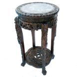 An oriental circular jardiniere stand, with inset rouge marble panel, on a heavily carved frame,